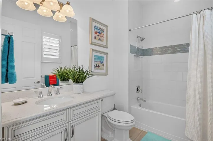Bathroom featuring vanity, shower / tub combo with curtain, light wood-type flooring, and  full mirror