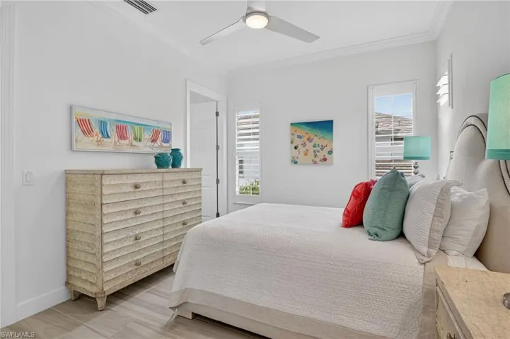 Bedroom featuring ornamental molding, a ceiling fan, and light floors and ensuite bath