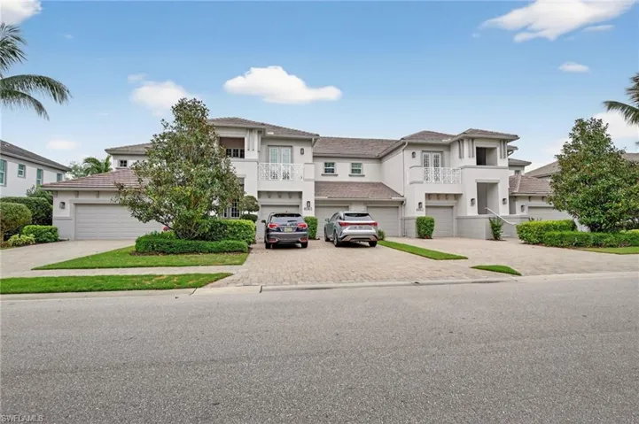 View of front facade featuring decorative paver driveway, stucco siding, a balcony, and a garage