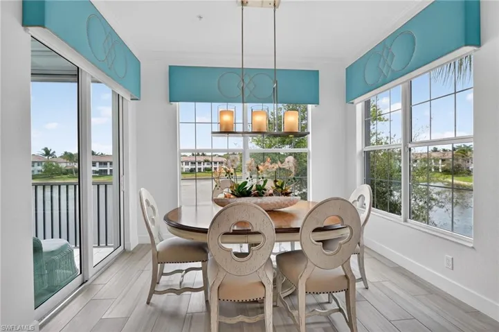 Dining space with a water view, wood look tiled floors, ornamental molding, and exquisite lighting