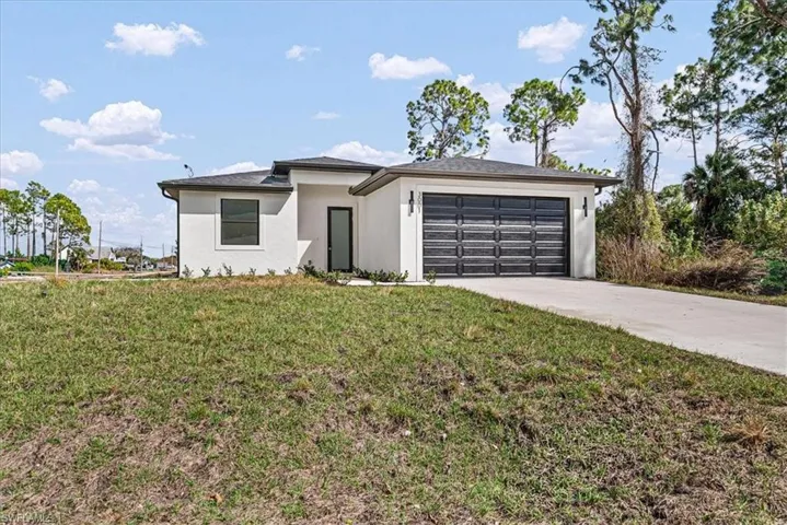 Prairie-style house with stucco siding, a garage, a front yard, and driveway