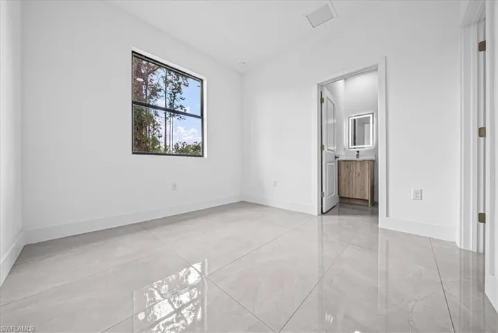 Unfurnished bedroom with ensuite bathroom and vaulted ceiling