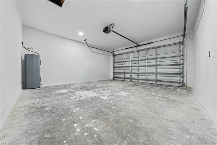 Garage featuring electric water heater, a textured wall, and a garage door opener