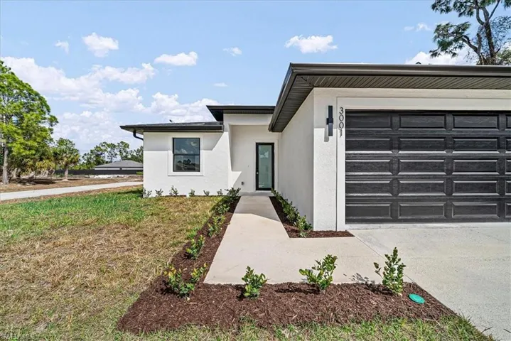 View of front of property featuring stucco siding, driveway, and an attached garage