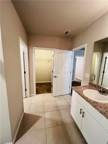 Bathroom featuring a spacious closet, vanity, and light tile patterned flooring