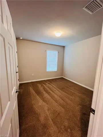 Empty room with dark colored carpet and baseboards