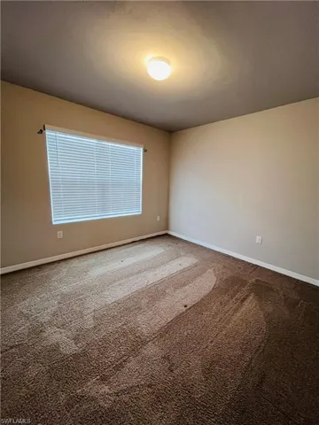 Carpeted spare room featuring baseboards