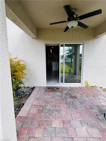 Property entrance with a patio, ceiling fan, and stucco siding