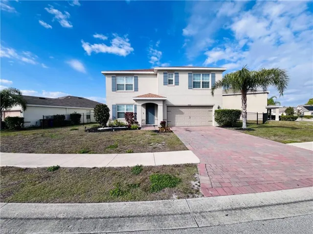View of front of home with stucco siding, decorative driveway, and a garage