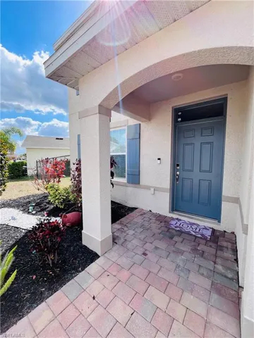 View of exterior entry featuring covered porch and stucco siding