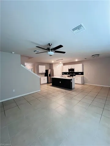 Unfurnished living room featuring light tile patterned floors and a ceiling fan