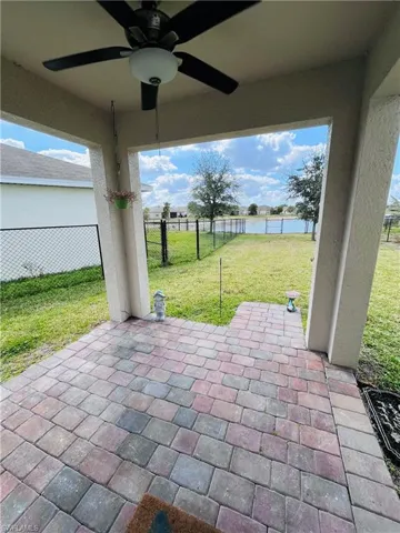 Fenced backyard with a ceiling fan, a patio, and a water view