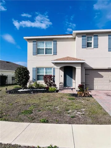 Traditional home featuring stucco siding, a garage, and driveway