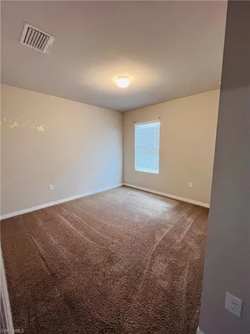 Spare room featuring carpet flooring and baseboards