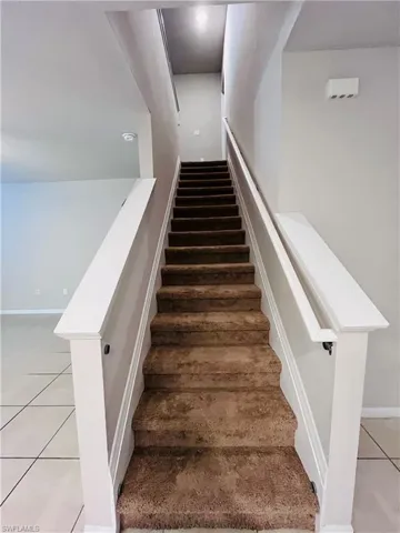 Staircase with tile patterned floors and baseboards