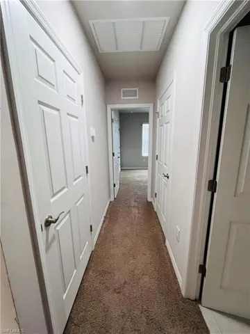 Hall featuring light colored carpet and baseboards
