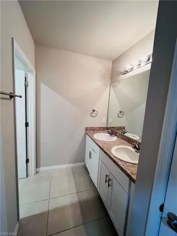 Bathroom with double vanity and light tile patterned flooring