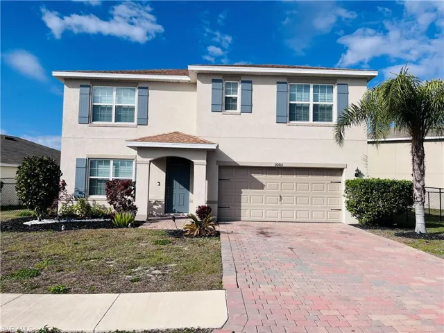 Traditional home with stucco siding, decorative driveway, and a garage