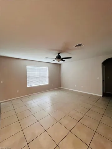 Spare room with ceiling fan, arched walkways, and light tile patterned floors