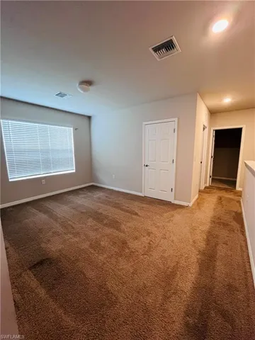 Unfurnished room featuring dark colored carpet and baseboards