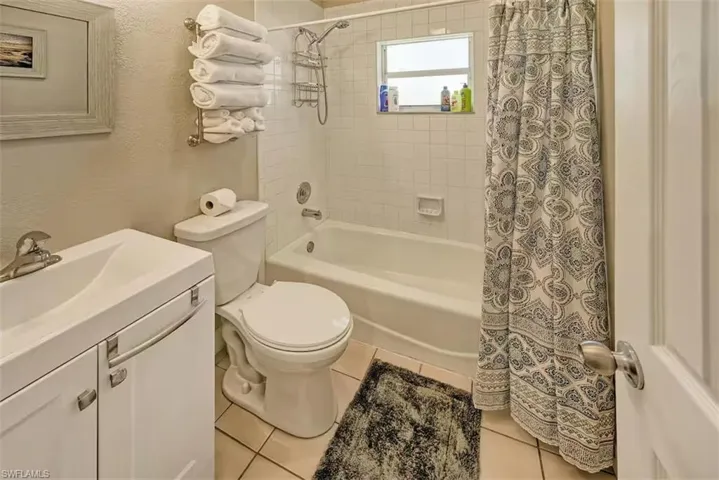 Bathroom with shower / tub combo with curtain, toilet, tile patterned floors, and vanity