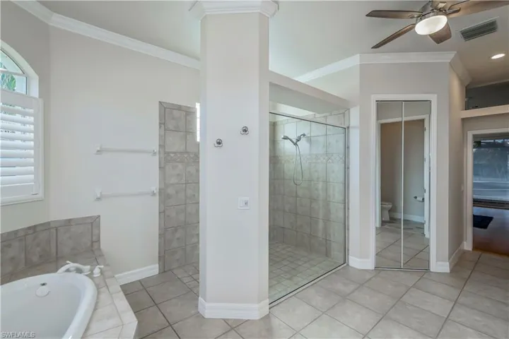 M-Bathroom featuring plus walk in shower, tile patterned floors, crown molding, ceiling fan, and toilet