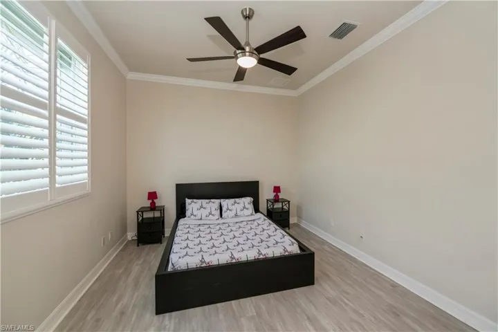 Bedroom with ceiling fan, Pergo flooring, and crown molding