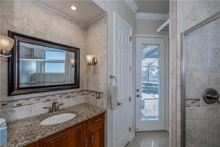 Bathroom featuring tile patterned flooring, vanity, a healthy amount of sunlight, and an enclosed shower