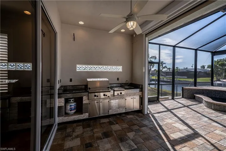 View of patio / terrace featuring ceiling fan, sink, exterior kitchen, a lanai, and a grill