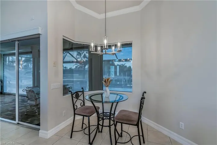 Tiled dining area featuring a chandelier and crown molding