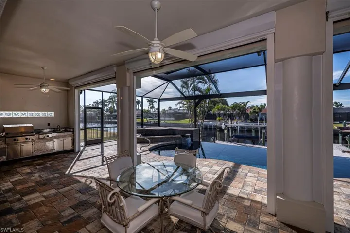 View of patio featuring grilling area, a water view, ceiling fan, a lanai, and area for grilling