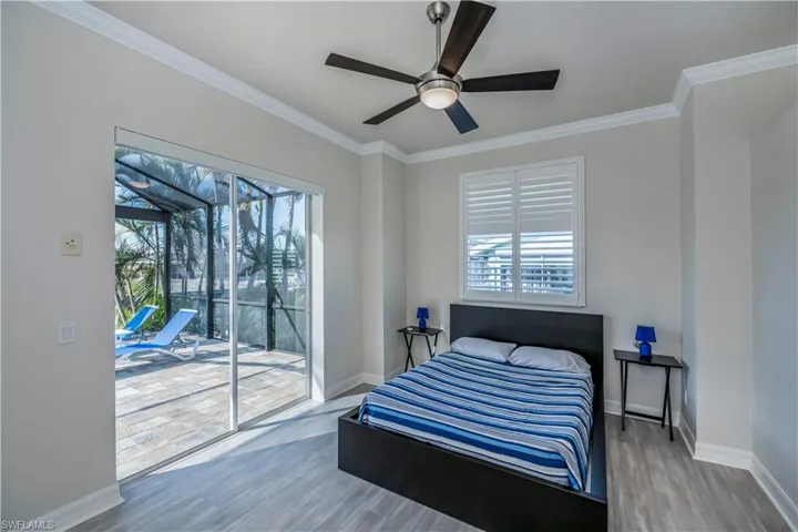 Bedroom with wood-type flooring, access to outside, ceiling fan, and ornamental molding