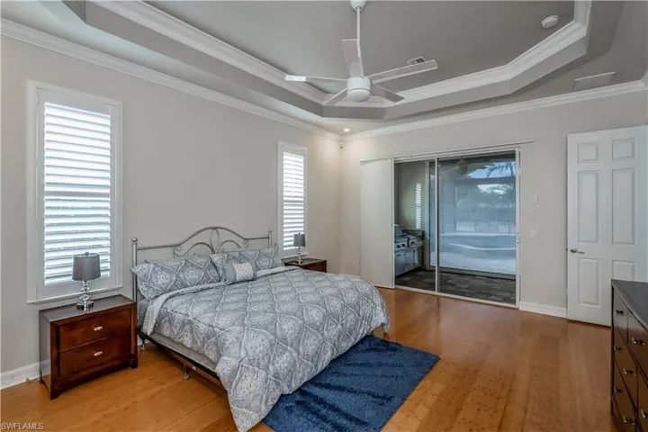 M-Bedroom featuring light bamboo flooring, access to outside, a raised ceiling, and ceiling fan