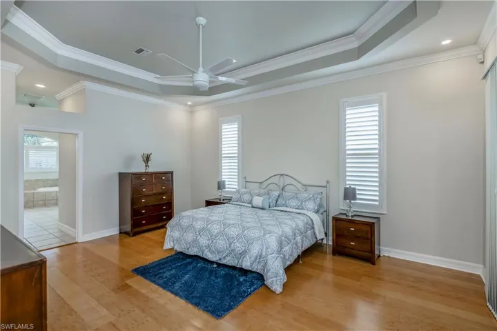 M-Bedroom with ensuite bath, a raised ceiling, ceiling fan, and ornamental molding