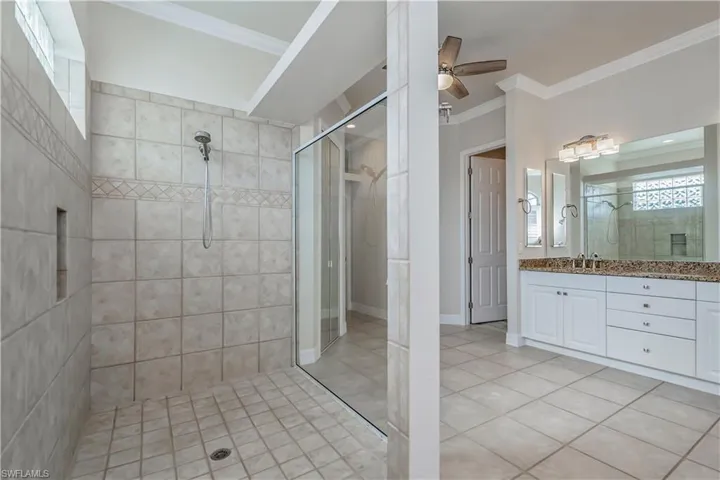 M-Bathroom with a tile shower, ceiling fan, tile patterned floors, crown molding, and vanity
