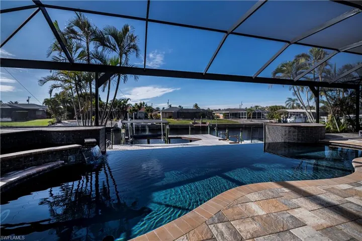 View of pool with glass enclosure, a water view, and a boat dock