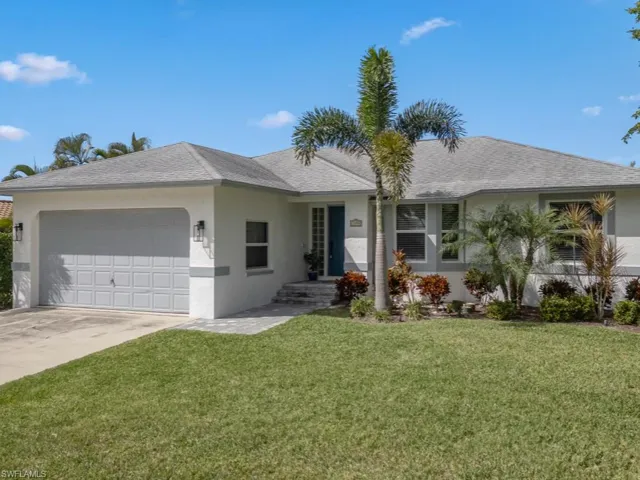 Ranch-style house with an attached garage, a front yard, and stucco siding