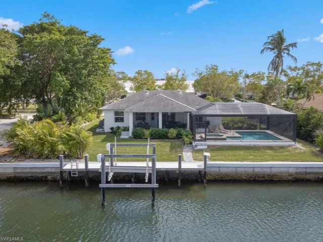 Rear view of house with a water view, an outdoor pool, a yard, and a patio