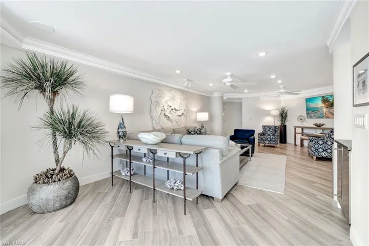 Living room with recessed lighting, ornamental molding, and light wood-style flooring