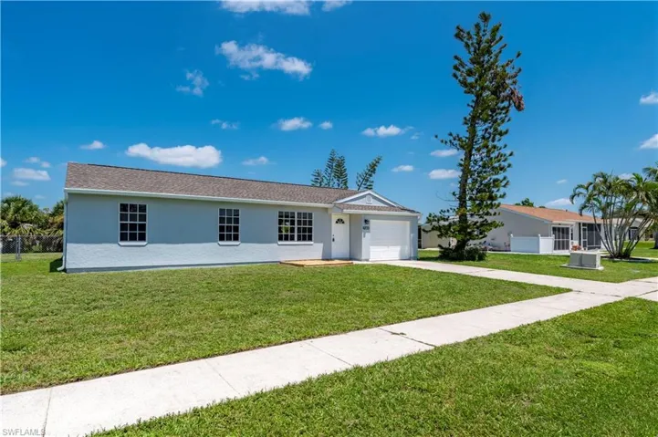 Ranch-style home featuring stucco siding, concrete driveway, fence, a garage, and a front lawn