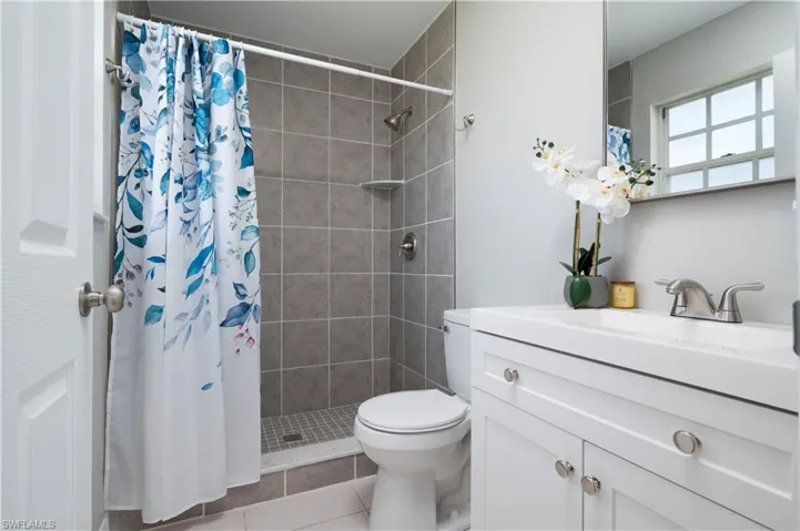 Bathroom with a stall shower, tile patterned flooring, vanity, and toilet