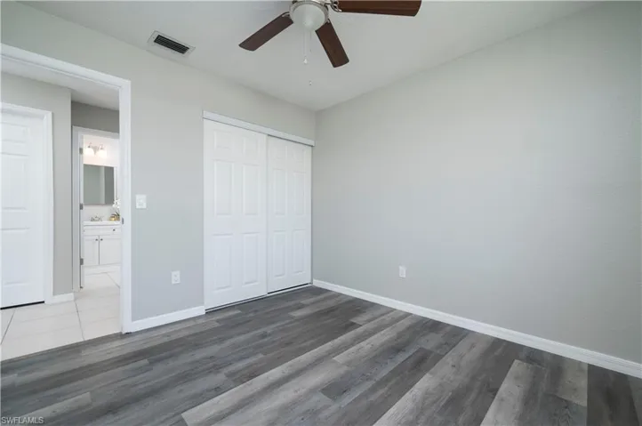 Unfurnished bedroom with baseboards, a closet, visible vents, and dark wood-style flooring