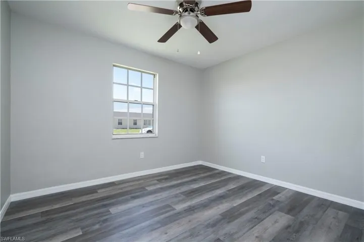 Unfurnished room with ceiling fan, baseboards, and dark wood finished floors