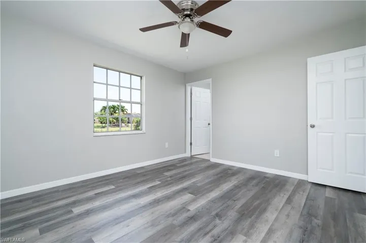 Spare room with dark wood-style floors, baseboards, and a ceiling fan