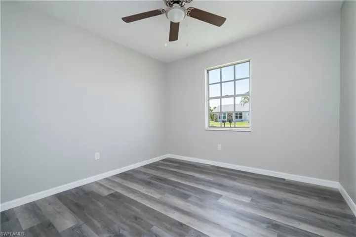 Unfurnished room featuring ceiling fan, dark wood-style flooring, and baseboards