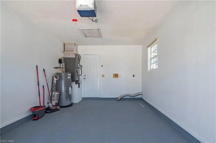 Garage with baseboards, electric water heater, and a garage door opener