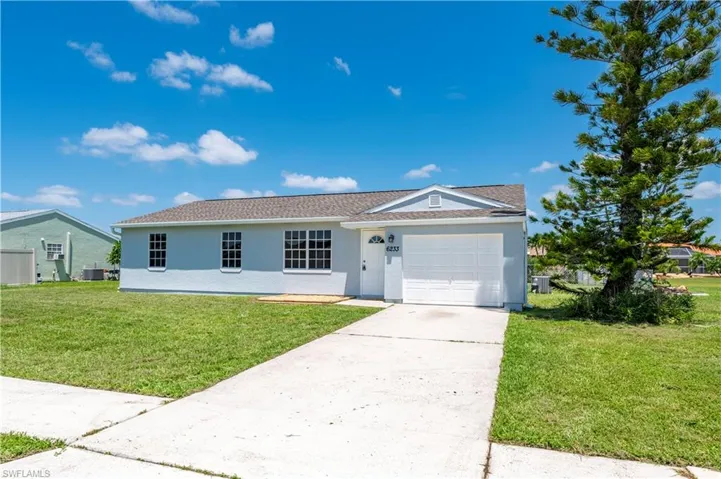 Ranch-style house with concrete driveway, an attached garage, a front lawn, and stucco siding