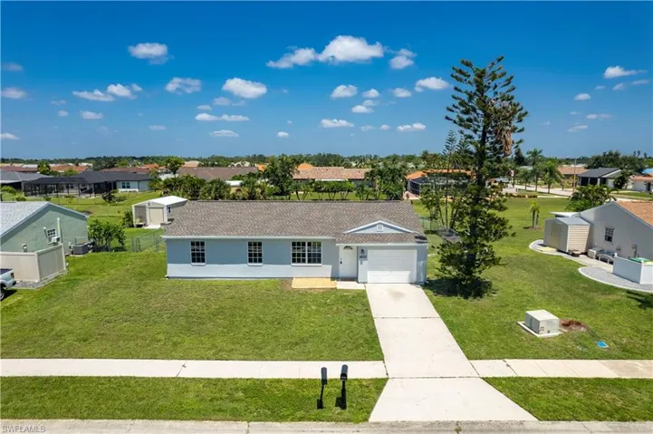 Ranch-style home featuring concrete driveway, a front yard, a residential view, and stucco siding