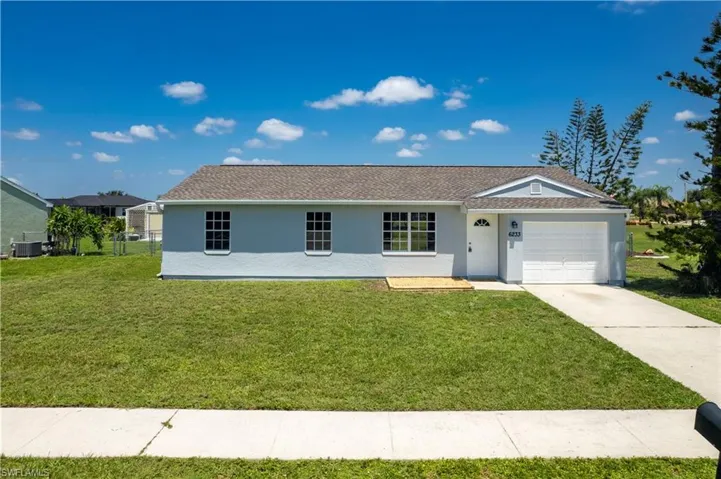 Ranch-style home featuring an attached garage, a front lawn, central AC unit, and stucco siding