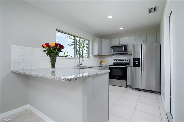 Kitchen with a peninsula, tasteful backsplash, appliances with stainless steel finishes, and a sink